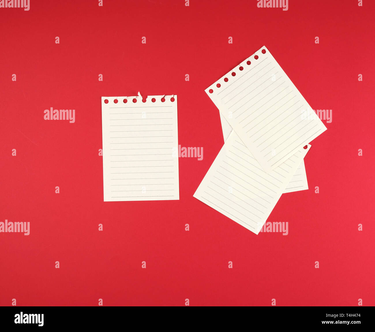 empty white sheets in a line torn out of notepad on a red background Stock Photo