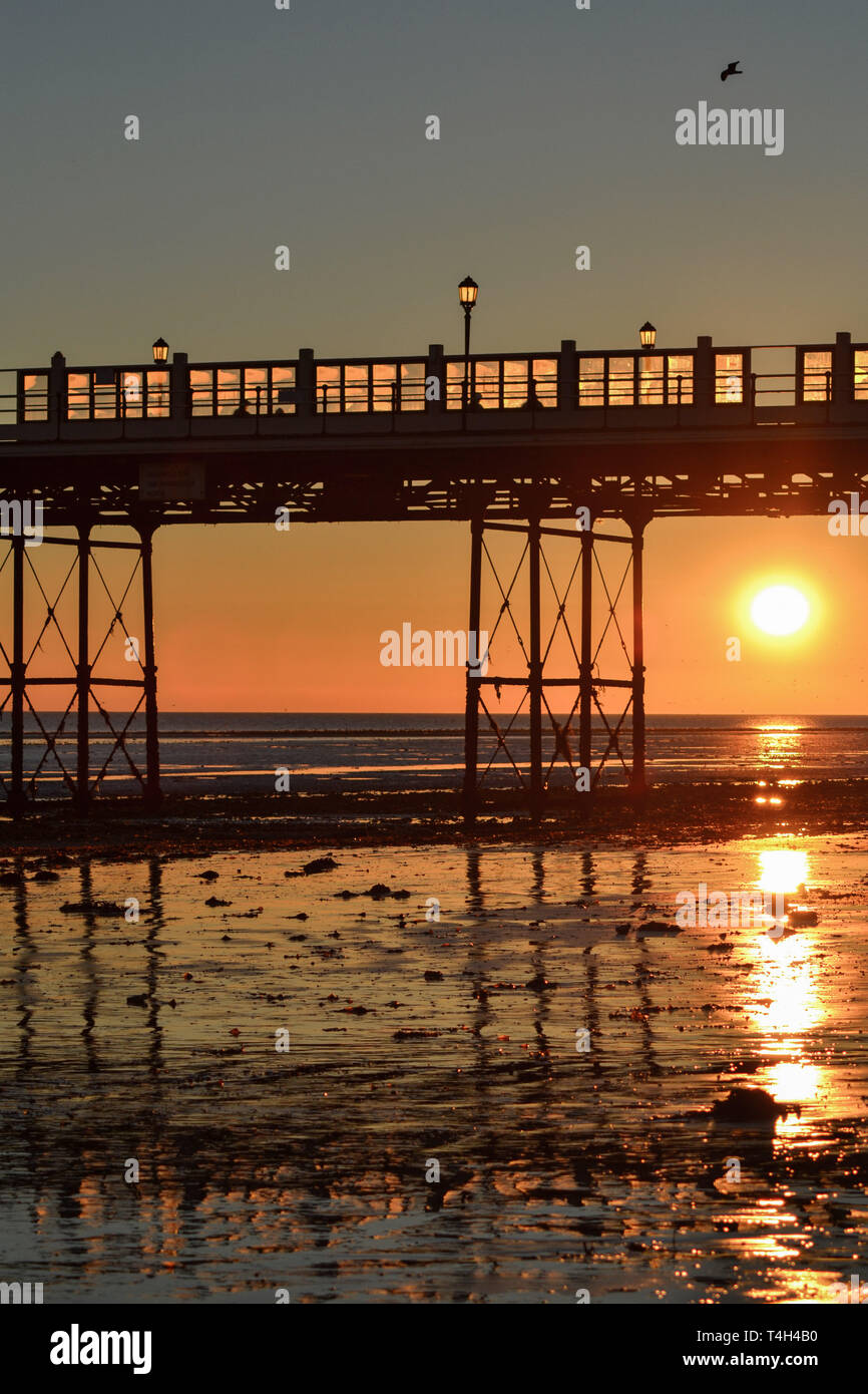 Looking under Worthing pier towards the sun setting Stock Photo