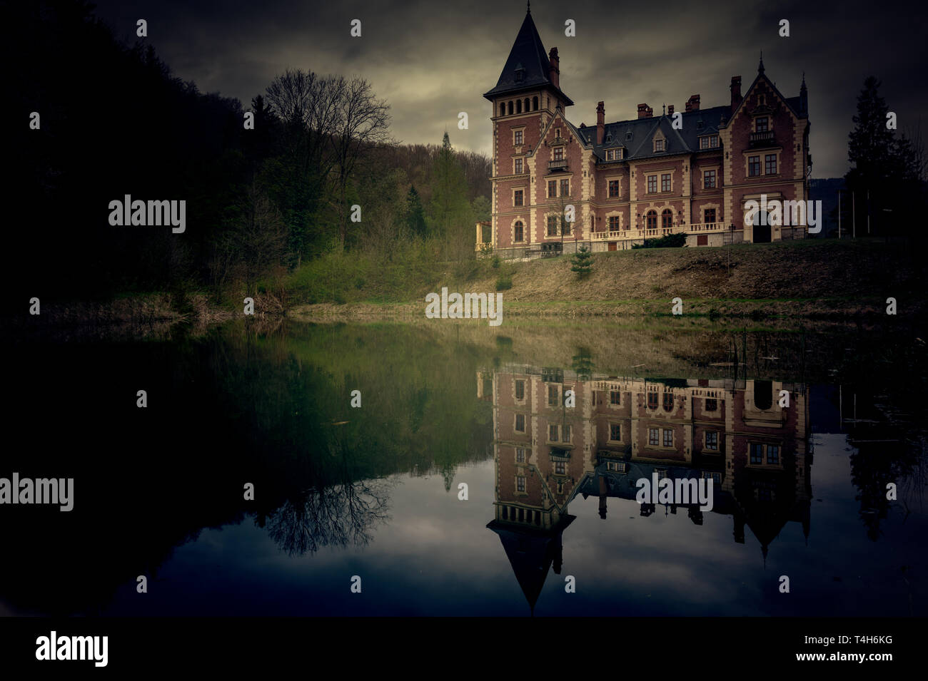 Scary view of a castle with a lake and reflection in the creepy forest Stock Photo