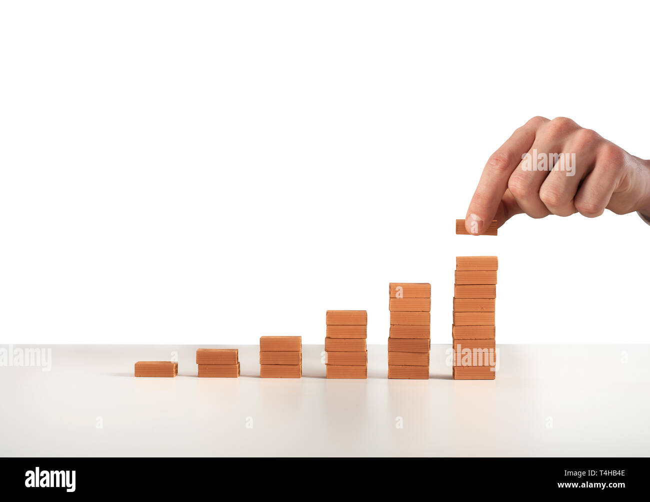 Businessman puts a brick on a bricks pile. Concept of growing statistics and success Stock Photo