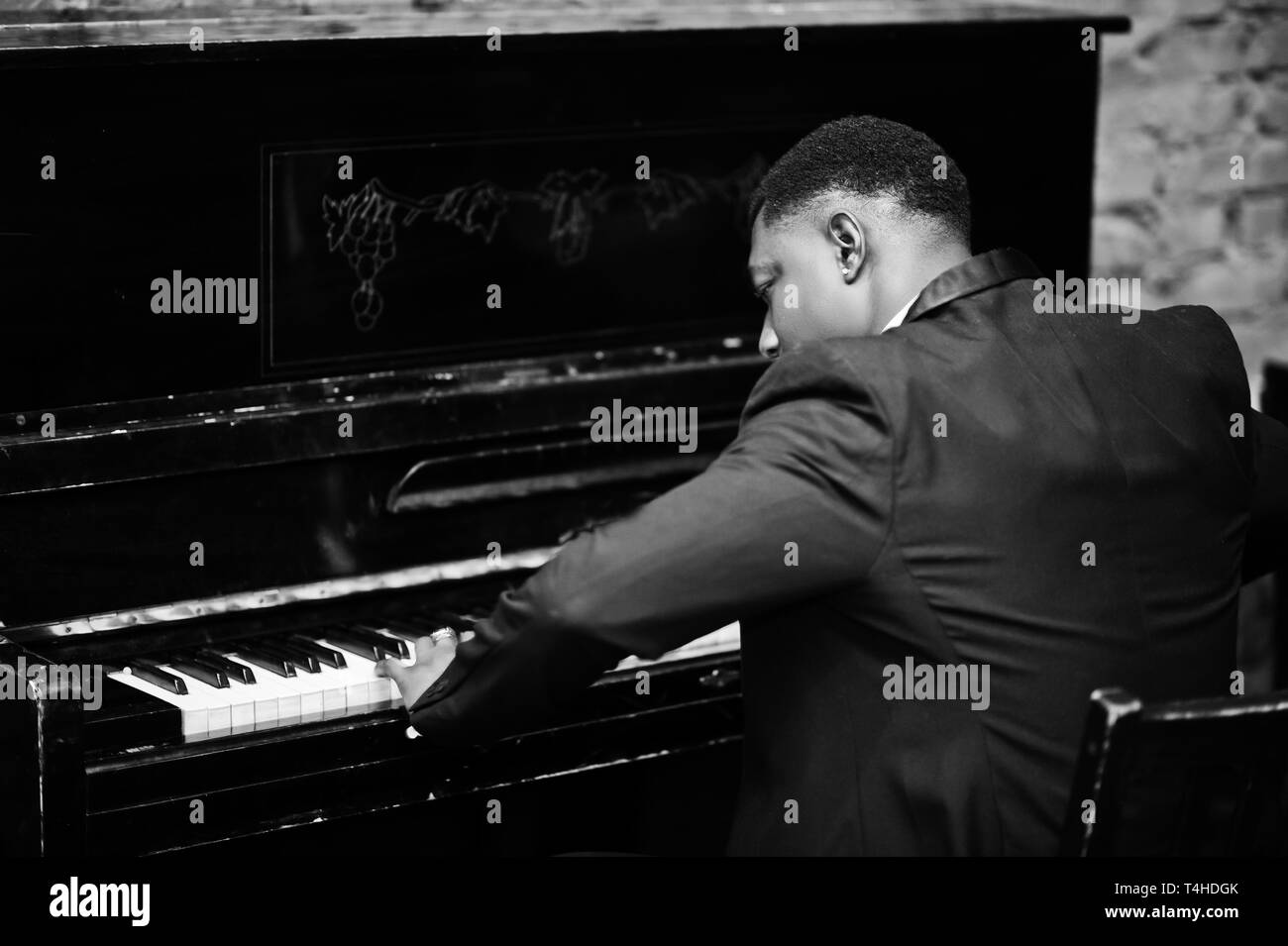 Back of strong powerful african american man in black suit play piano