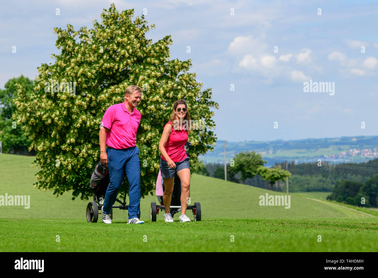 Good-humoured couple on the way on golf course Stock Photo