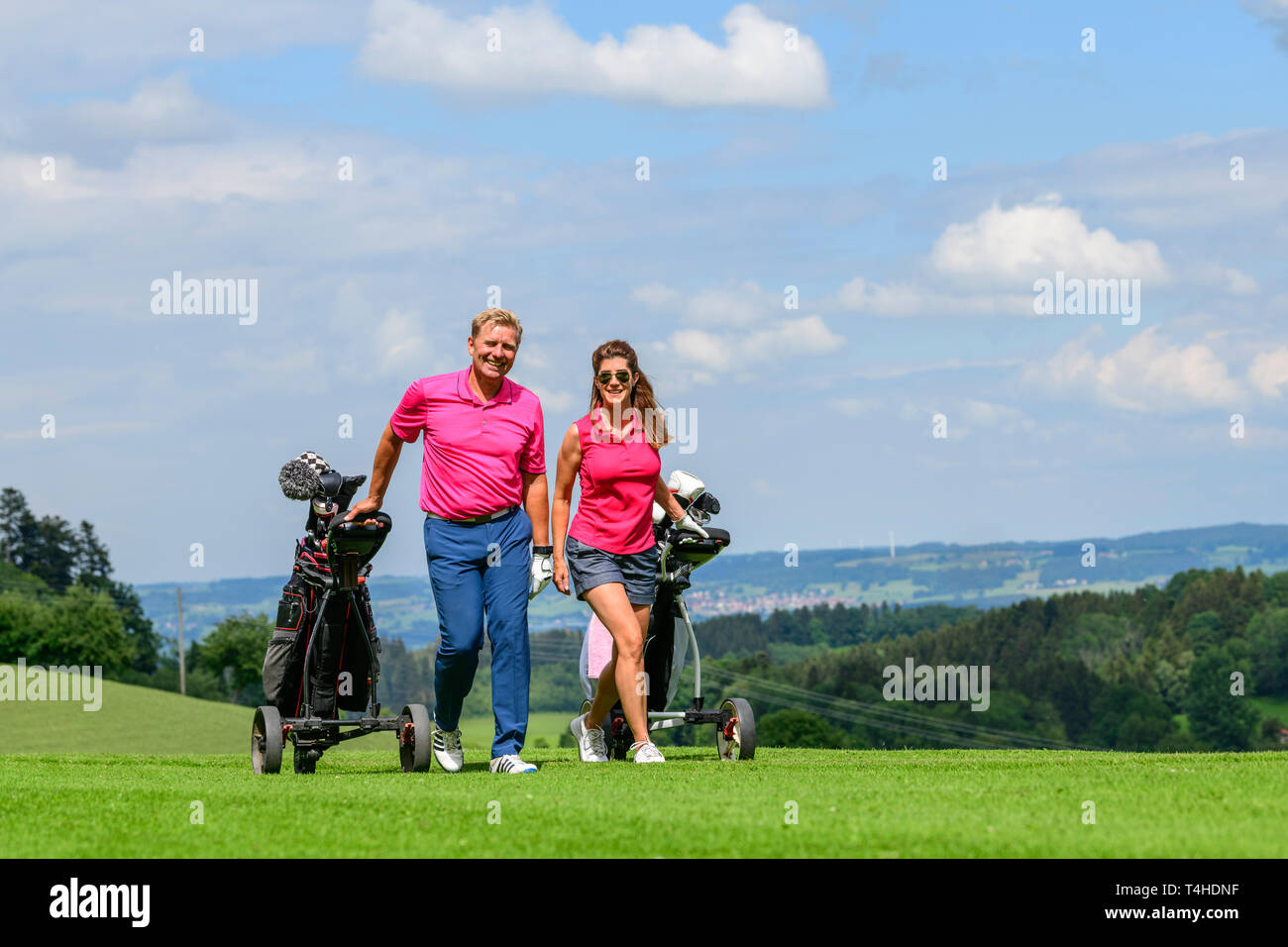 Good-humoured couple on the way on golf course Stock Photo