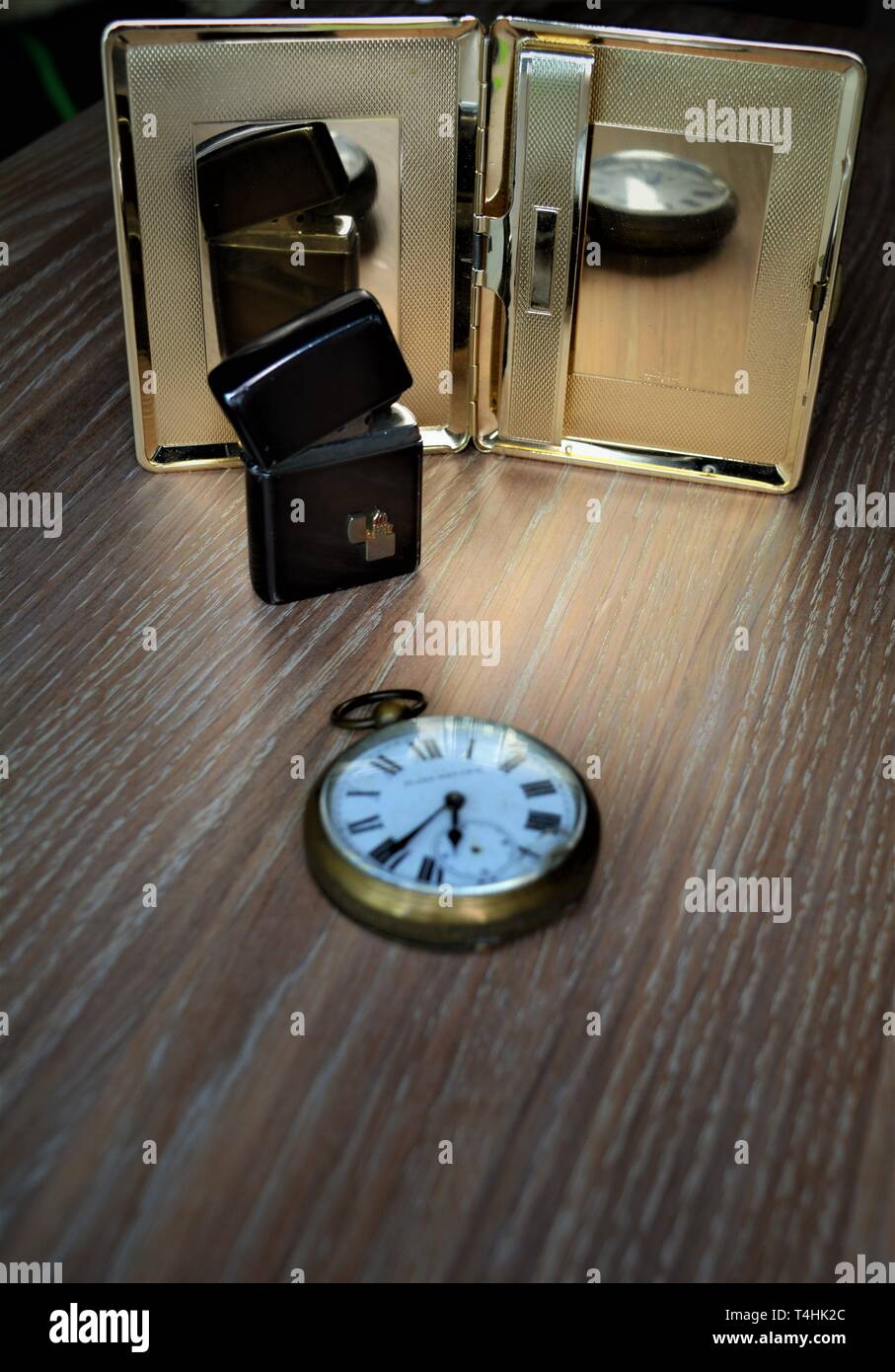 Pocket watch, lighter and cigarette case still life. Reflections from
