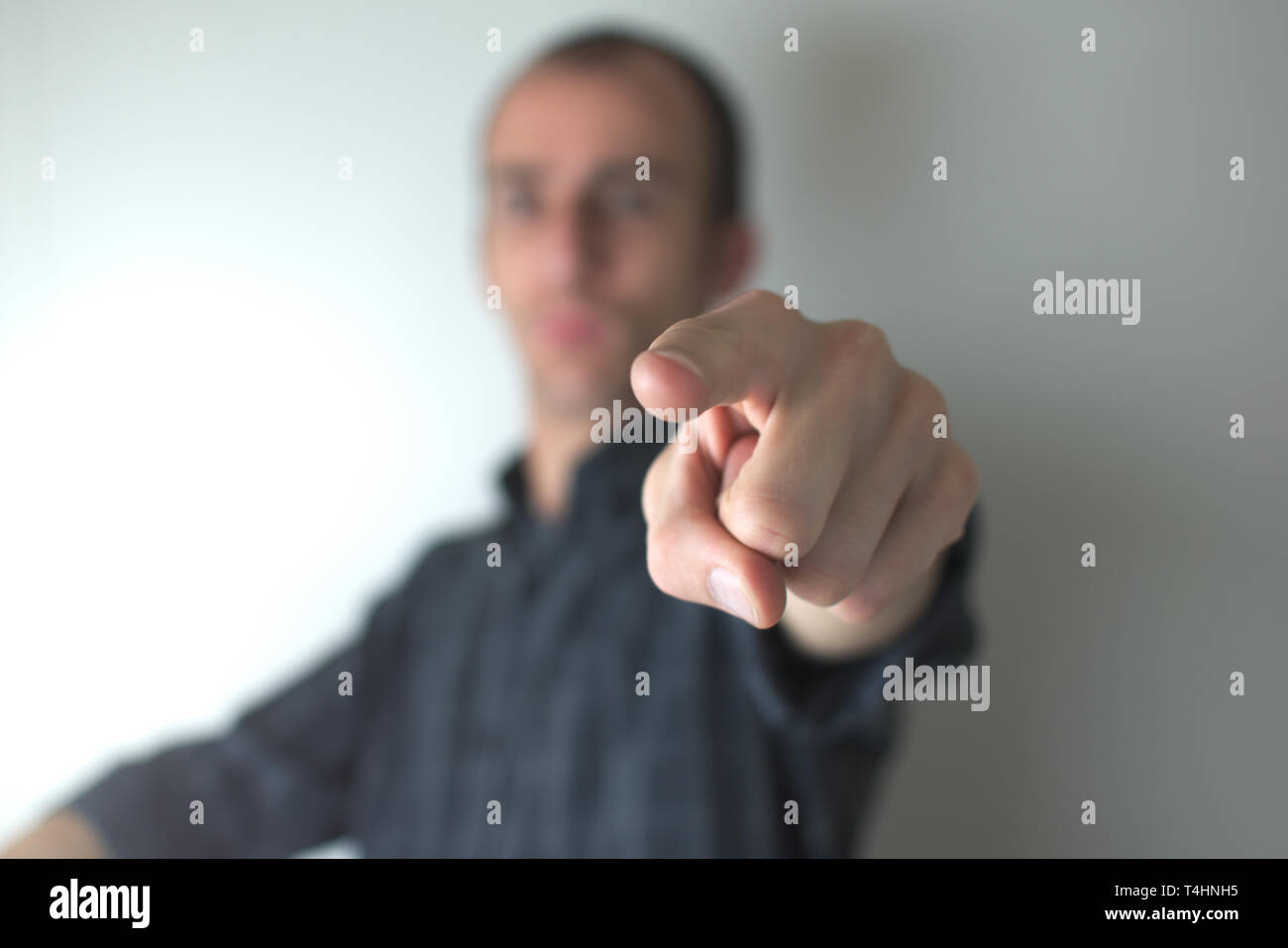A man on black shirt pointing toward the viewer. Stock Photo
