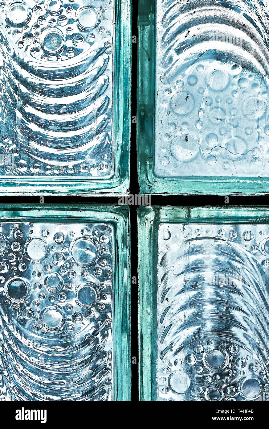 Detail of fixed blue colored glass block bricks with texture of flowing lines and bubbles, photographed against the cool bright light Stock Photo