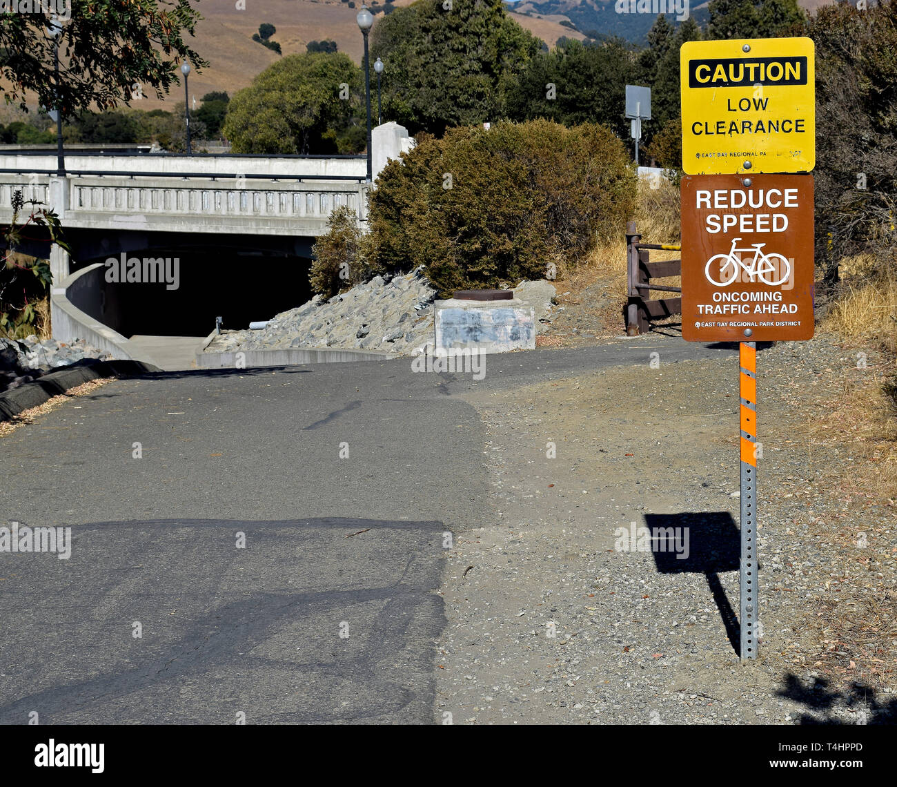 Alameda Creek Trail signs for bicycles to reduce speed and caution low clearance,  California Stock Photo