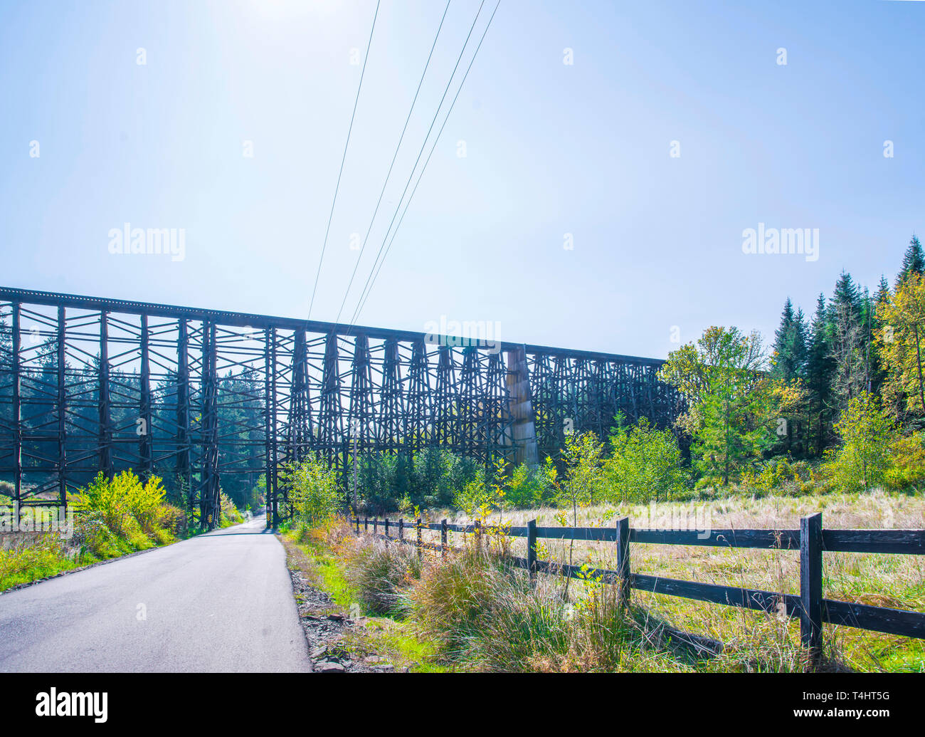 Landscape with a local road passing through the valley under a unique old build existing Holcomb creek wooden train trestle, allowing simultaneous mov Stock Photo