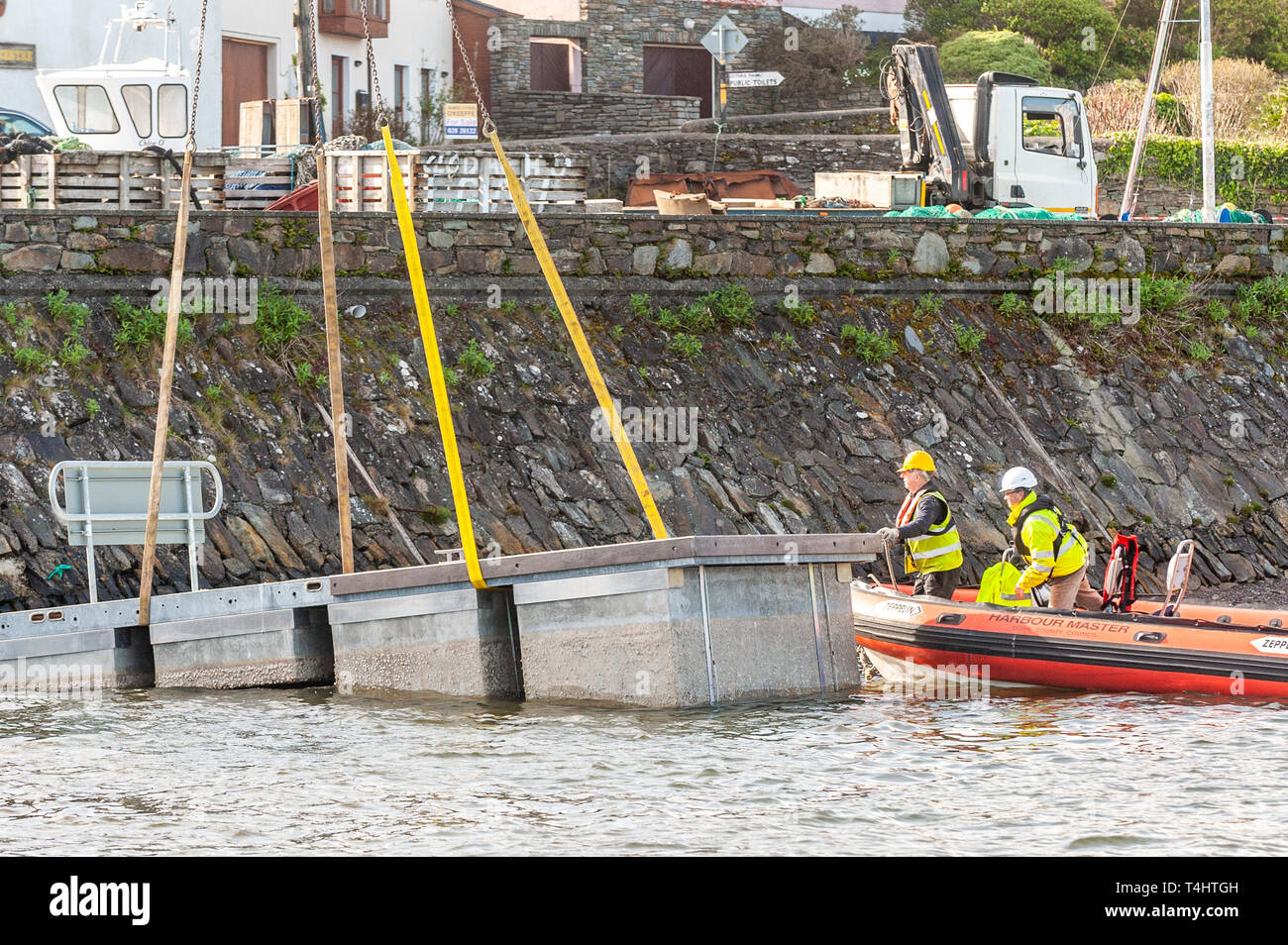 Schull, West Cork, Ireland. 16th Apr, 2019. West Cork Civil Engineering were given the task of refloating the €600,000 Schull pontoon, ready for the season.  Workers are seen lifting a piece of the pontoon into the water, ready to be floated into position. Credit: Andy Gibson/Alamy Live News. Stock Photo