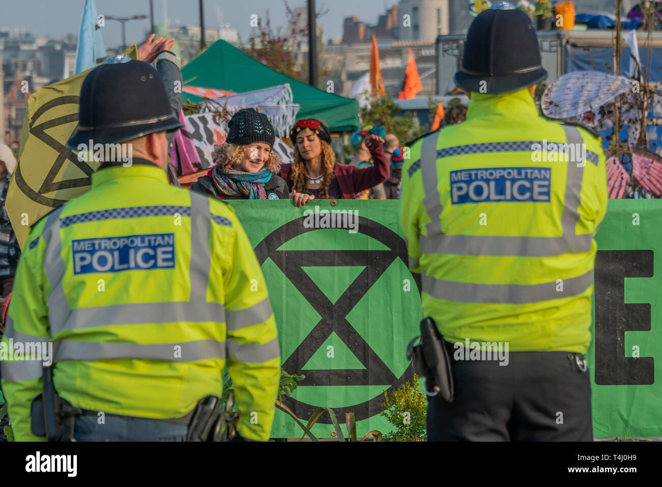 London, UK. 17th Apr 2019. Already the banners of the road block are up and the police in place - Morning on Waterloo Bridge sees the camp awake and commuters make their progress on foot and bike across the river - Day 3 - Protestors from Extinction Rebellion block several junctions in London as part of their ongoing protest to demand action by the UK Government on the 'climate chrisis'. The action is part of an international co-ordinated protest. Credit: Guy Bell/Alamy Live News Stock Photo