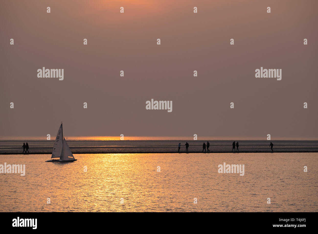 West Kirby, Wirral, UK. April 17, 2019. People enjoying an evening walk at the marine lake in West Kirby on the Wirral in north west England on Wednesday, April 17, 2019 as temperatures are set to rise ahead of the upcoming bank holiday weekend. Credit: Christopher Middleton/Alamy Live News Stock Photo