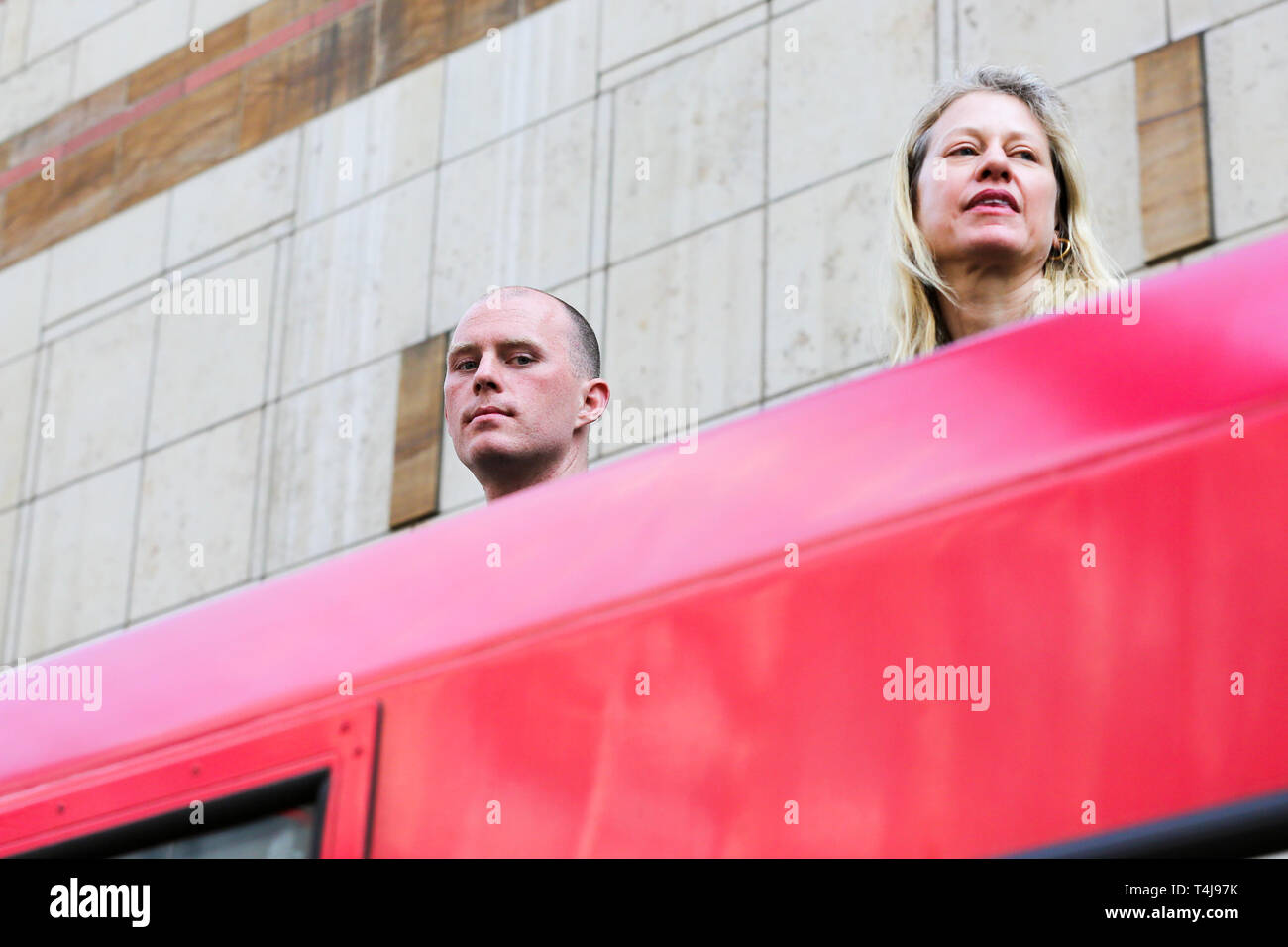 Two environmental activists are seen on the roof of a Docklands Light Railway train at Canary Wharf station during the third day of the Extinction Rebellion Climate Change protest.  The group is demanding decisive action from the UK Government on the environmental crisis. Stock Photo