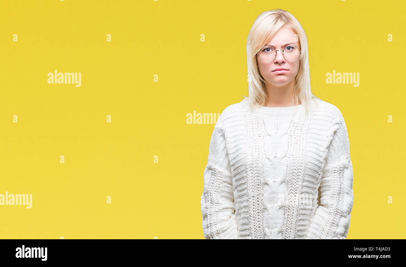 Young beautiful blonde woman wearing winter sweater and glasses over isolated background skeptic and nervous, frowning upset because of problem. Negat Stock Photo