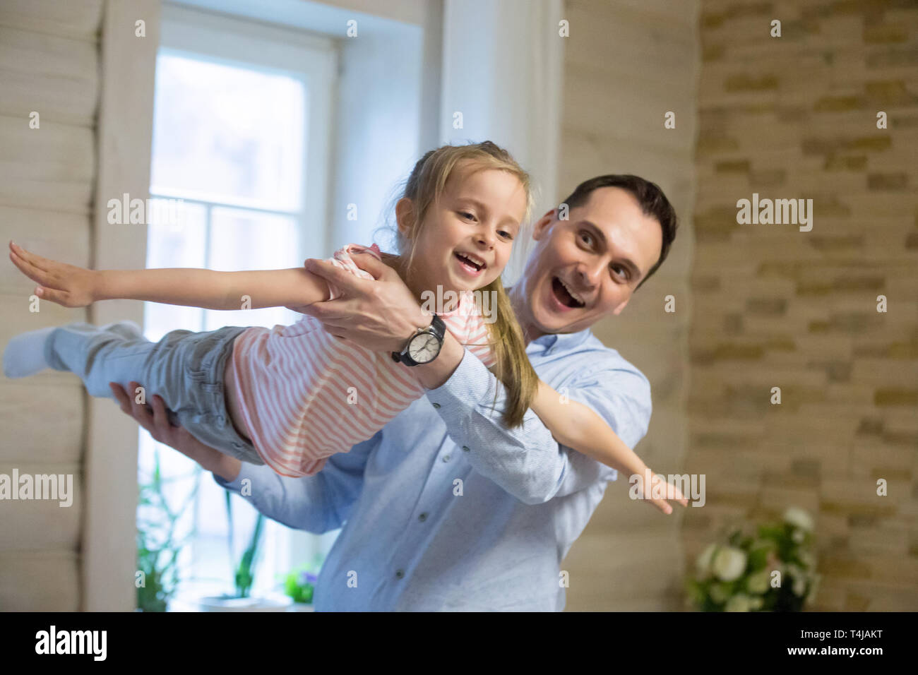 Overjoyed father and daughter playing on weekend at home Stock Photo