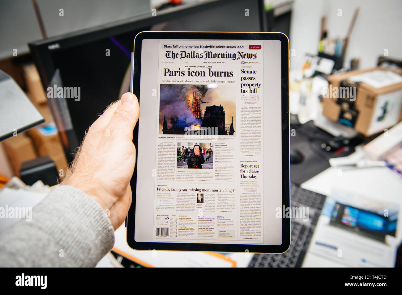 Paris, France - Apr 15, 2019: Man reading THe Dallas Morning News on iPad Pro Apple News Plus digital newspaper featuring on cover Notre-Dame Cathedral on fire causing damages the famous spire to collapse Stock Photo