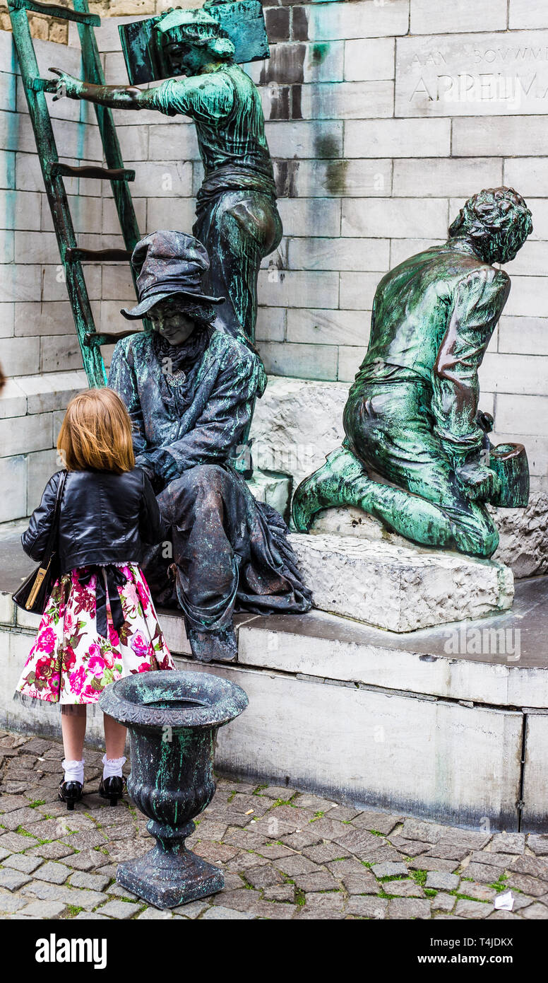 Antwerp Belgium. Street performer pretending to be a statue. A young girl goes to talk to woman dressed as statue Stock Photo