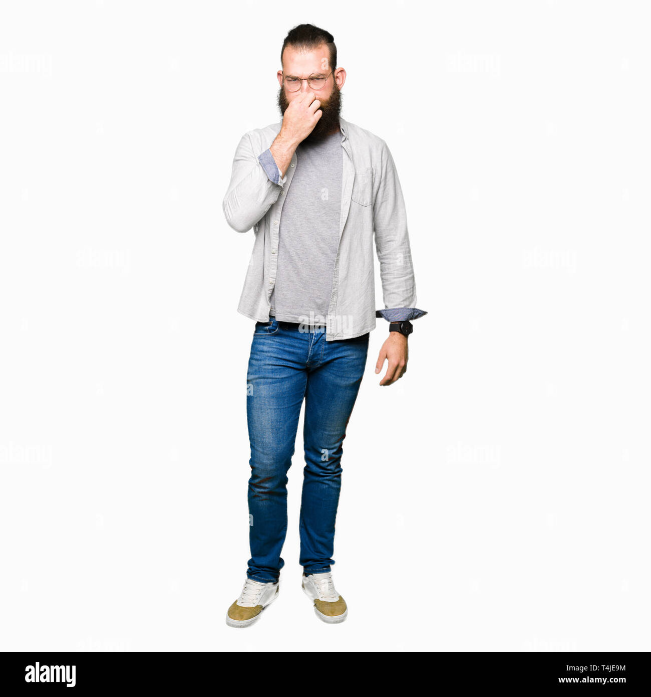 Young blond man wearing glasses smelling something stinky and