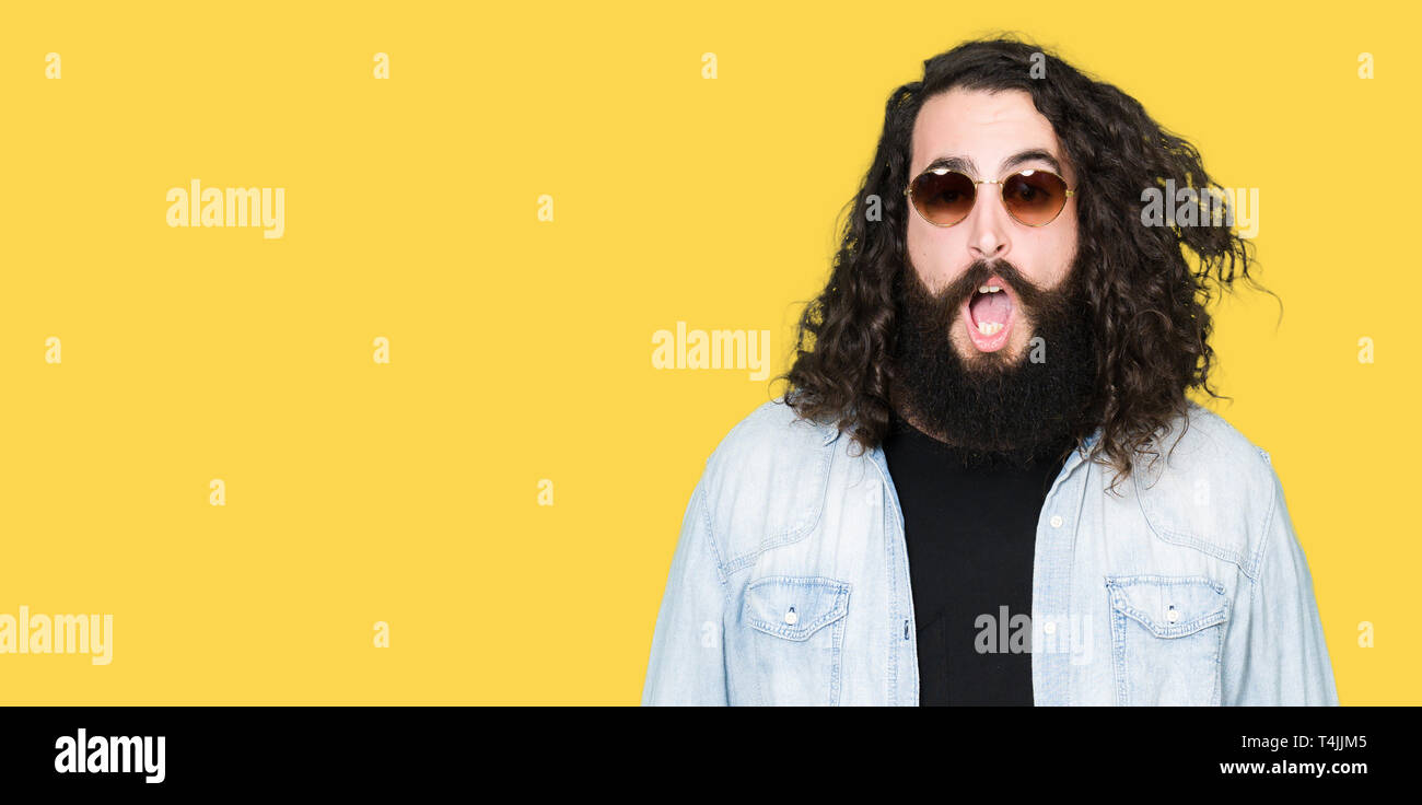 Young Hipster Man With Long Hair And Beard Wearing Sunglasses