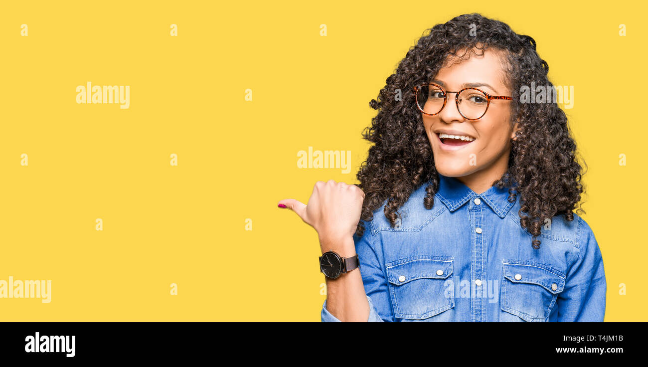 Young beautiful woman with curly hair wearing glasses smiling with ...