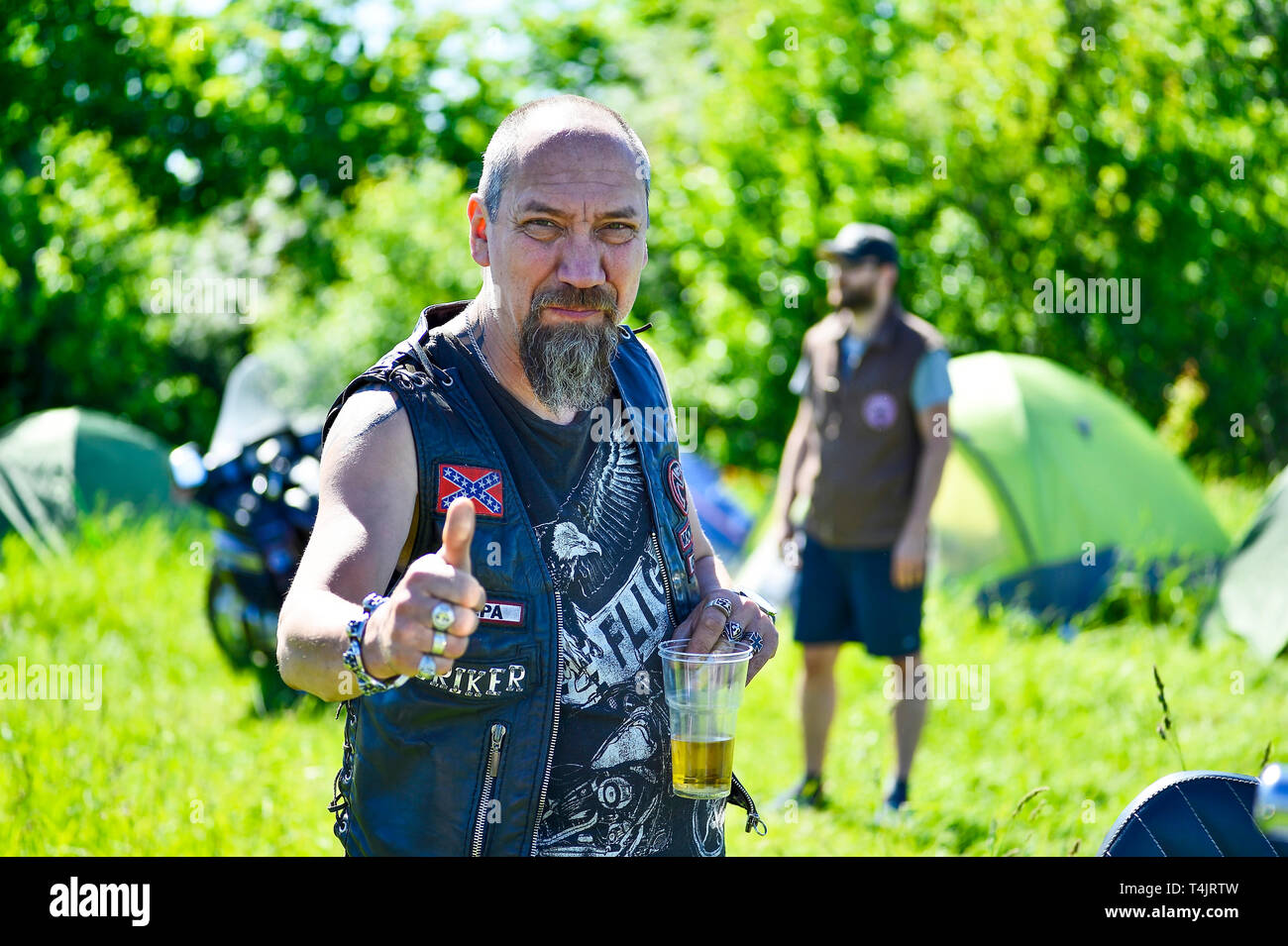 Man biker holding a glass of beer at the festival Meeting of summer Russia, Kursk region, Zheleznogorsk, may 2018. The concept of life on wheels. Stock Photo