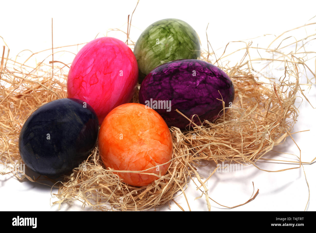 Colourfully painted Easter eggs with straw Stock Photo