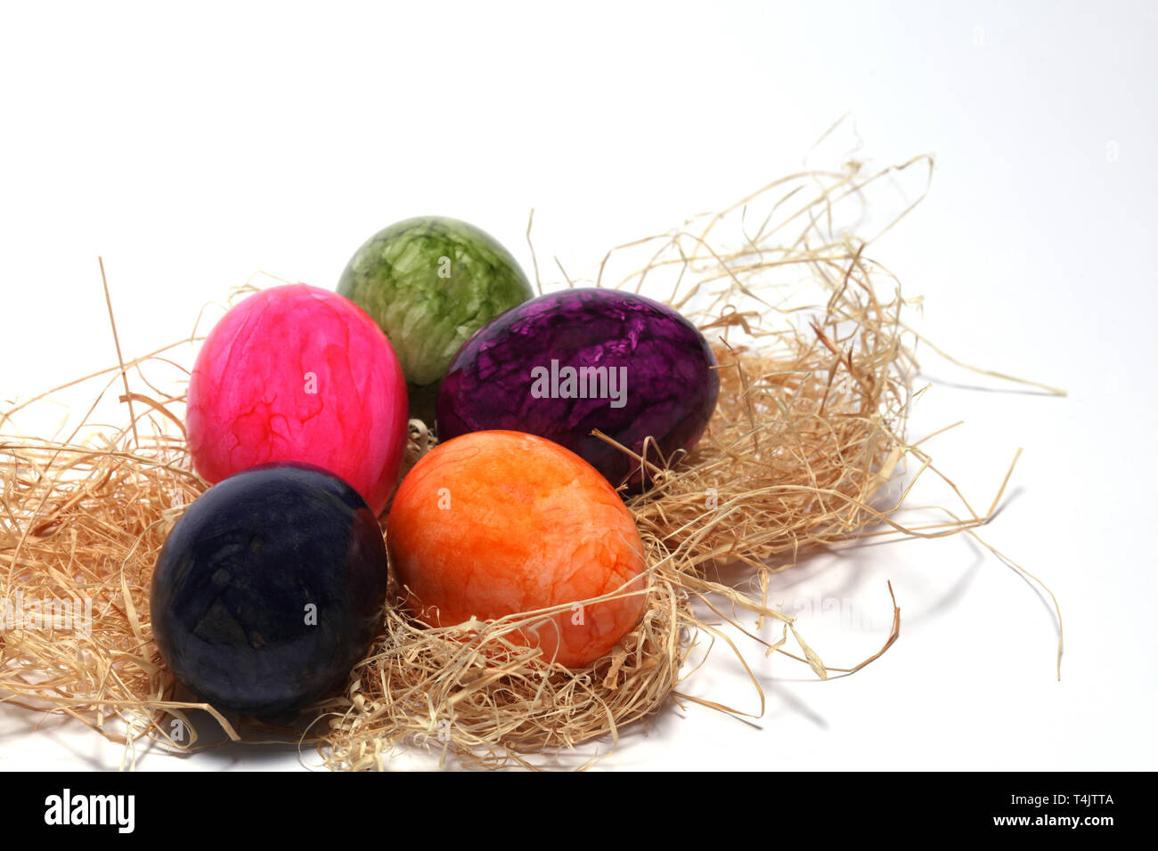 Colourfully painted Easter eggs with straw Stock Photo