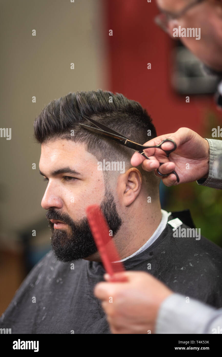 Handsome Bearded Man Having Hair Cut By Scissors At Barber Shop