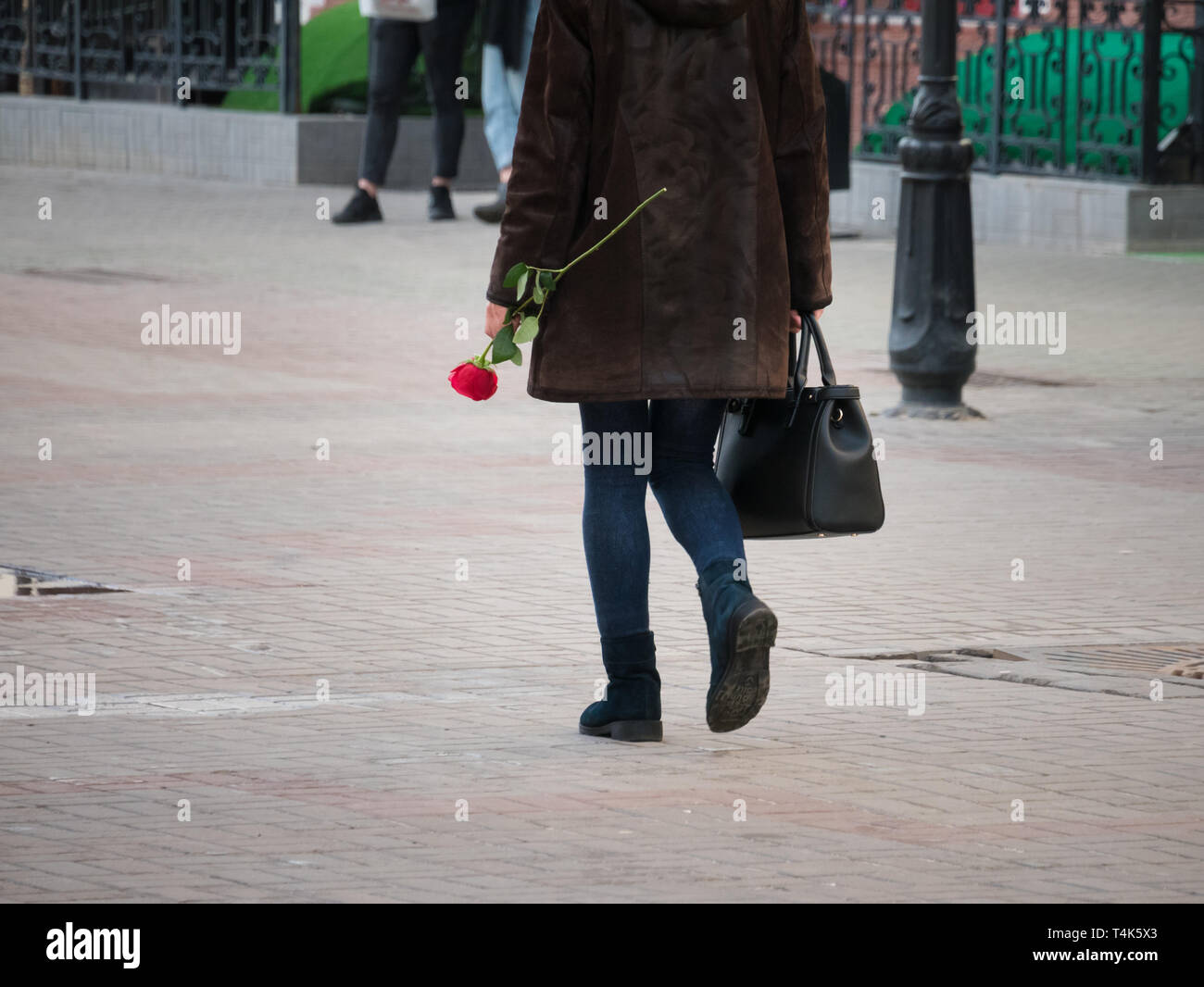 Urban streets. A woman walking on the street holding a rose Stock Photo ...