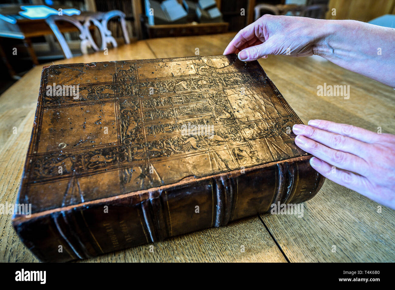 A copy of an intricate leather embossed book featuring castles and mythical beasts from 1519 in Salisbury Cathedral's 15th century library, where an ongoing project to catalogue, clean and find out more about the rare book collection is underway. Stock Photo
