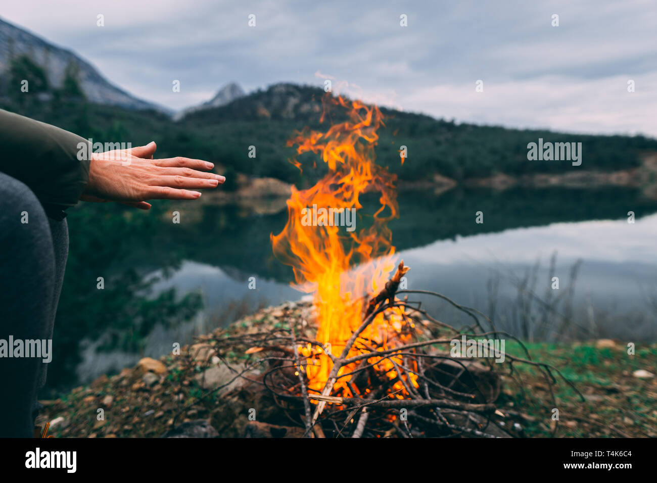 Hands of young woman warming up by camp fire.Body parts of adult female at nature. Camping. Stock Photo
