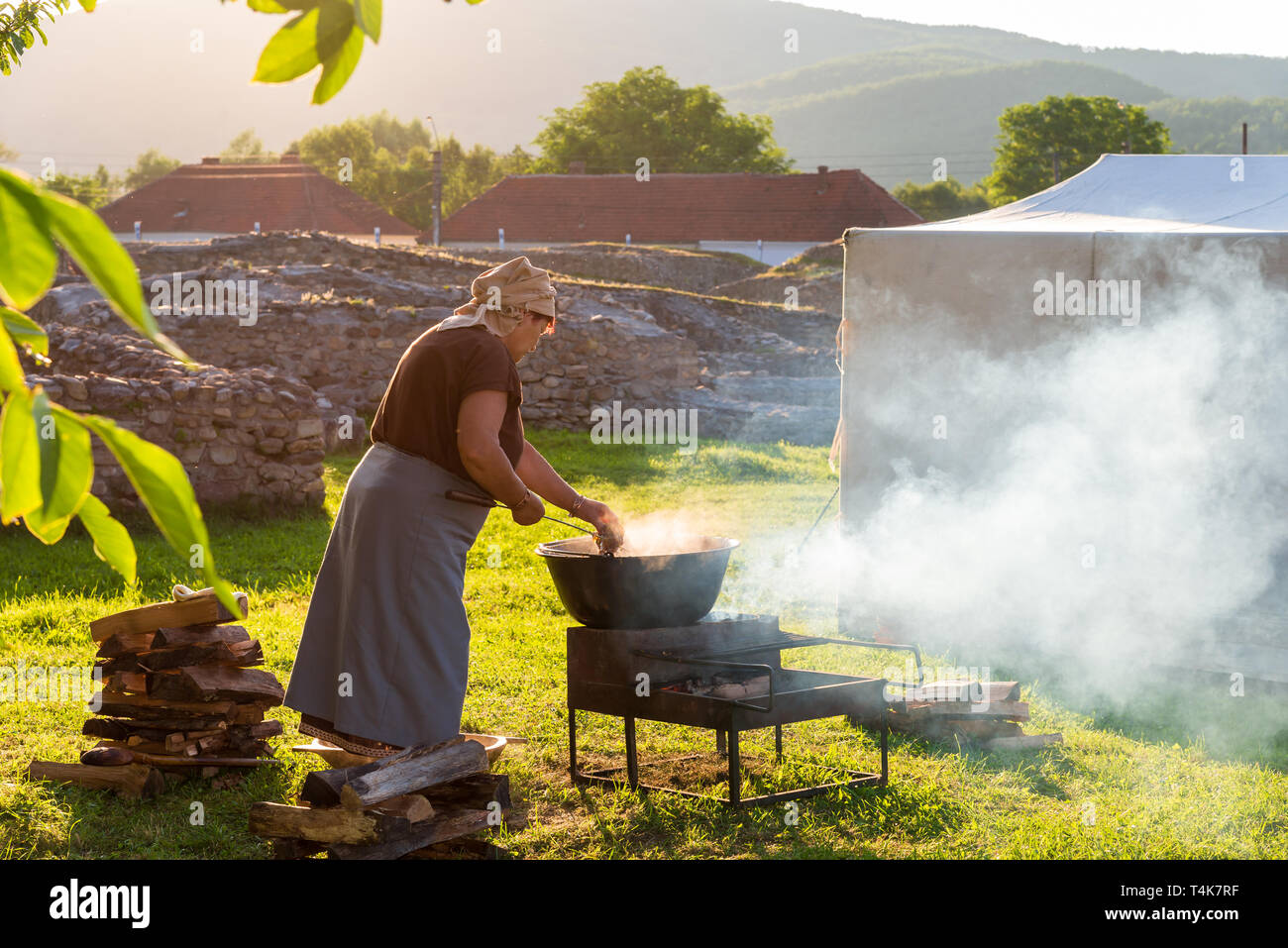 Woman cooking romanian traditional food on fire outdoor in a camping holiday in summer season Stock Photo