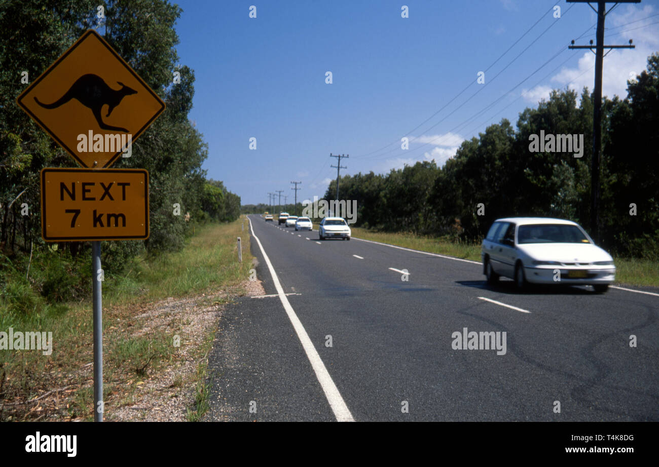 CARS TRAVELLING ALONG COUNTRY ROADS IN NEW SOUTH WALES, AUSTRALIA AND ROAD SIGN ADVISING THAT KANGAROOS MAY BE ON THE ROAD FOR THE NEXT 7 KMS. Stock Photo