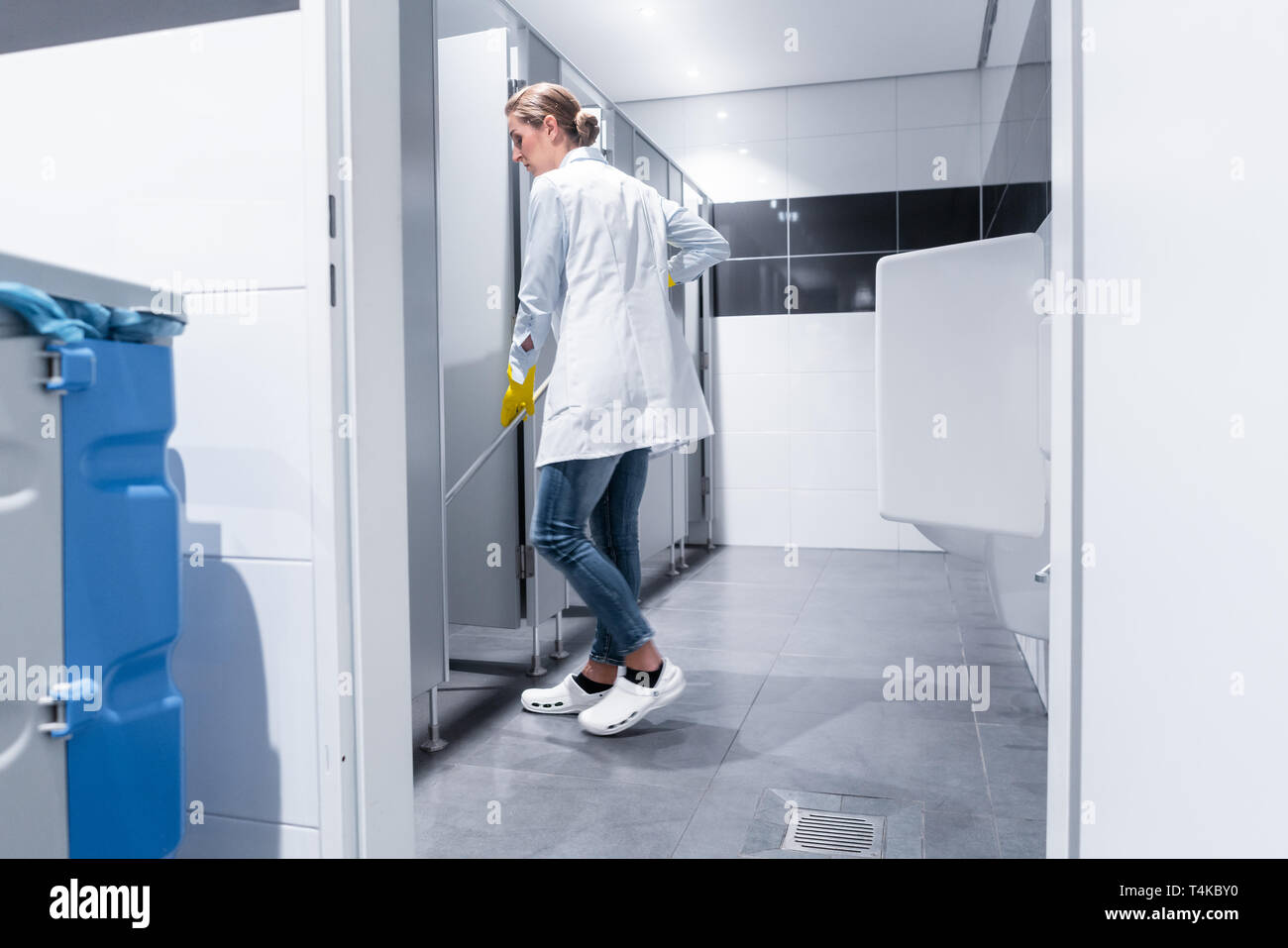 Cleaning lady or janitor mopping the floor in restroom Stock Photo