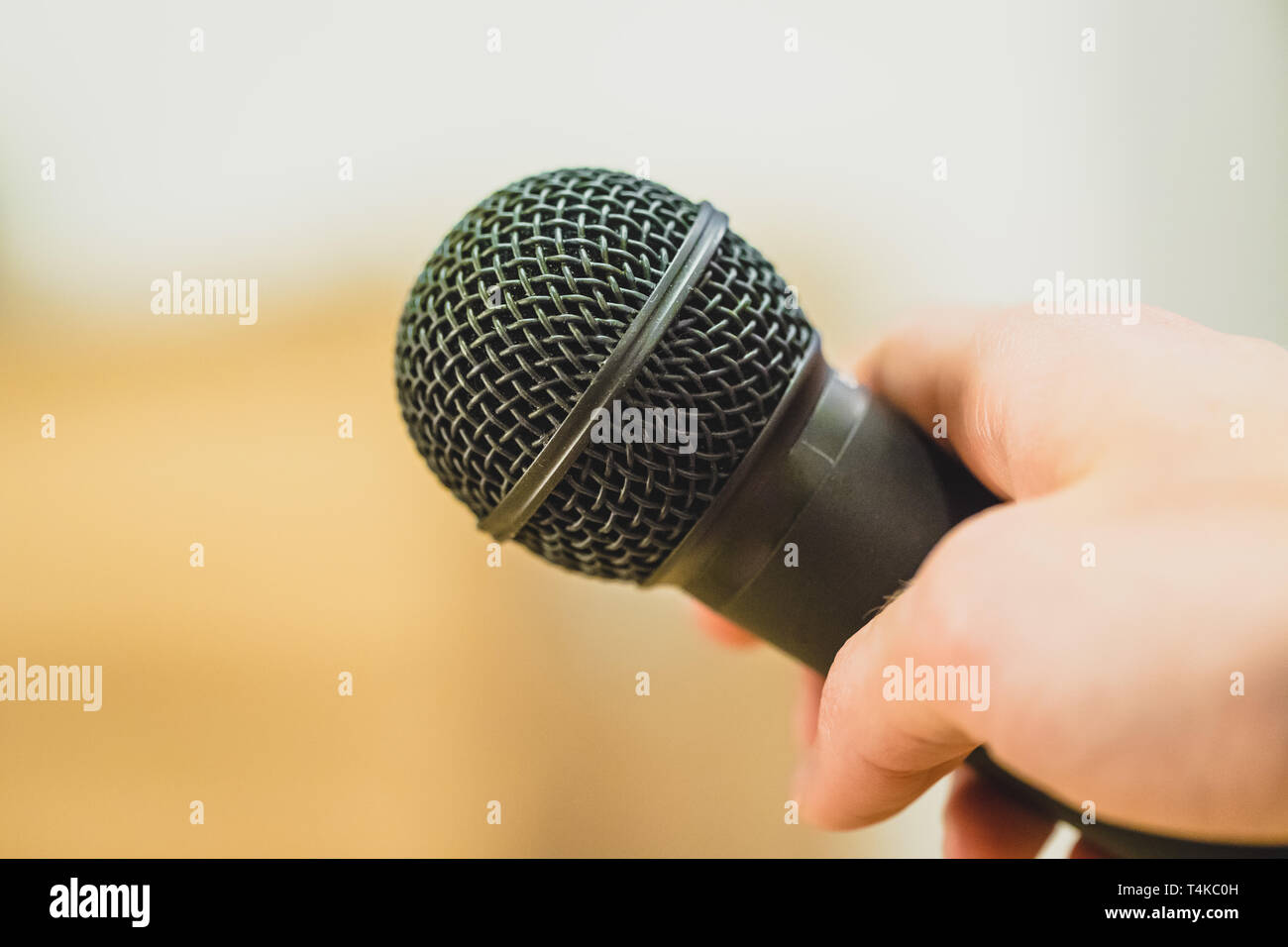 Close up picture of a hand which is holding a black microphone. Stock Photo