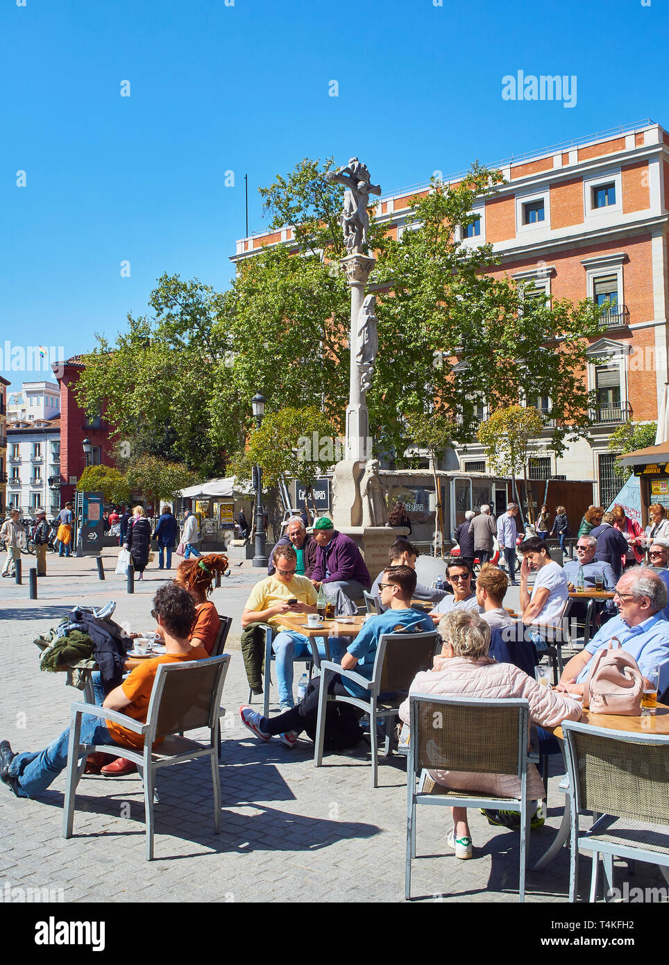 People refreshing on a terrace in the Jacinto Benavente square of Madrid with the Way of Saint James crossroad stone in the background. Stock Photo