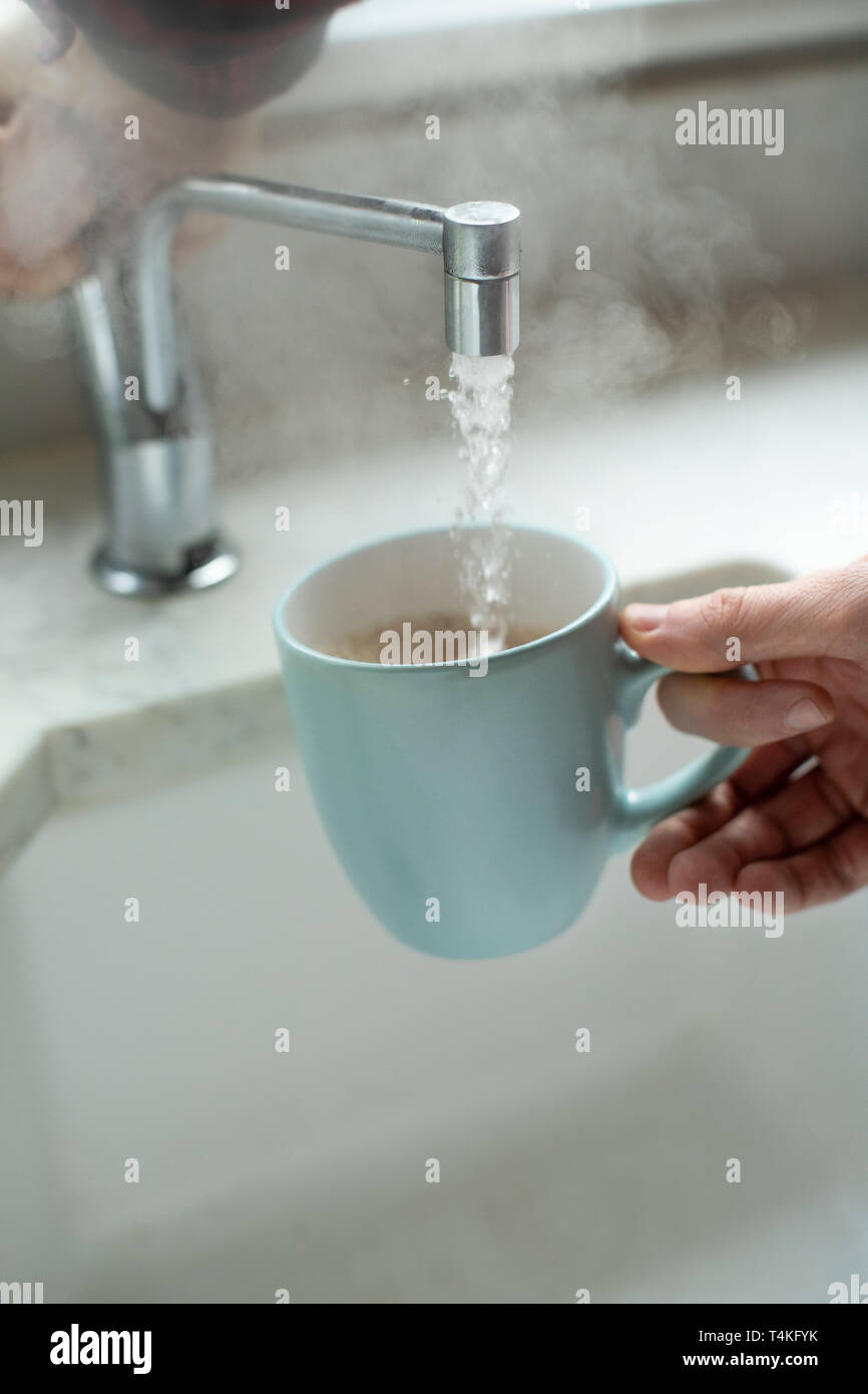 Close Up Of Man Making Hot Drink From Boiling Water Tap Stock Photo