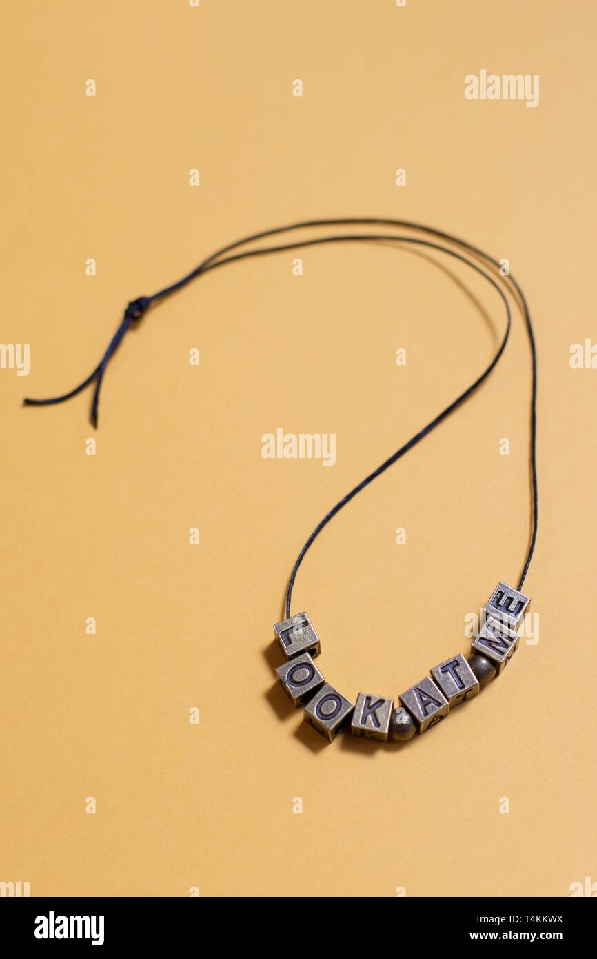 The words "look at me" spelled out by letter beads on a necklace. Stock Photo