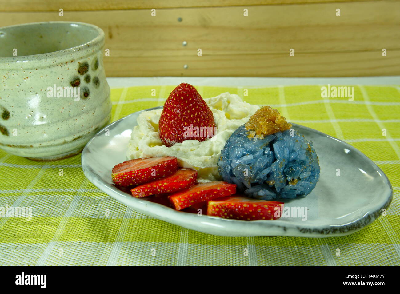 Blue pea sticky rice minced fish with coconut milk served with strawberry and whip cream, thai dessert asian food styling. Stock Photo