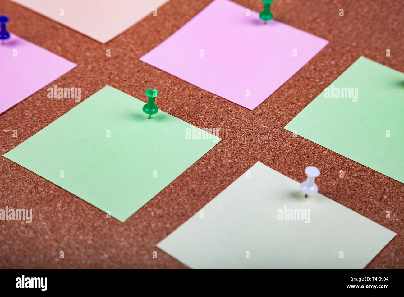 Corkboard with notes. Colored paper on corkboard. Stock Photo