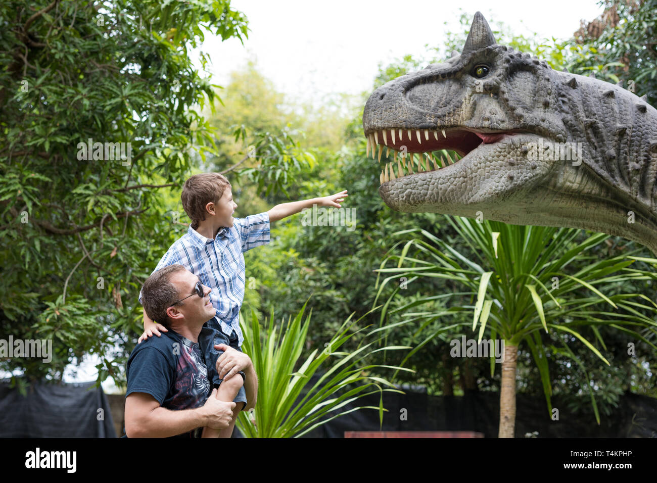 Happy father and son playing in the adventure dino park at the day time. People having fun outdoors. Concept of summer vacation and friendly family. Stock Photo