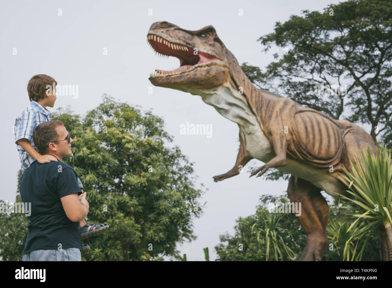 Happy father and son playing in the adventure dino park at the day time. People having fun outdoors. Concept of summer vacation and friendly family. Stock Photo