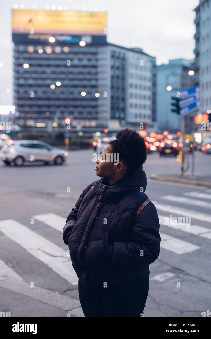 young and beautiful black girl in the street with curly hair looking ahead - expressive, metropolitan, observing Stock Photo