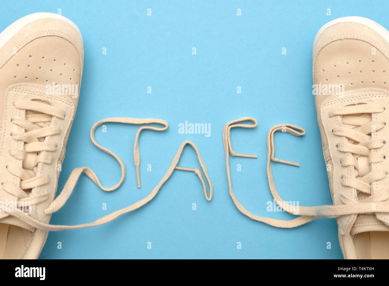 New women sneakers with laces in staff text. Flat lay on blue background. Stock Photo