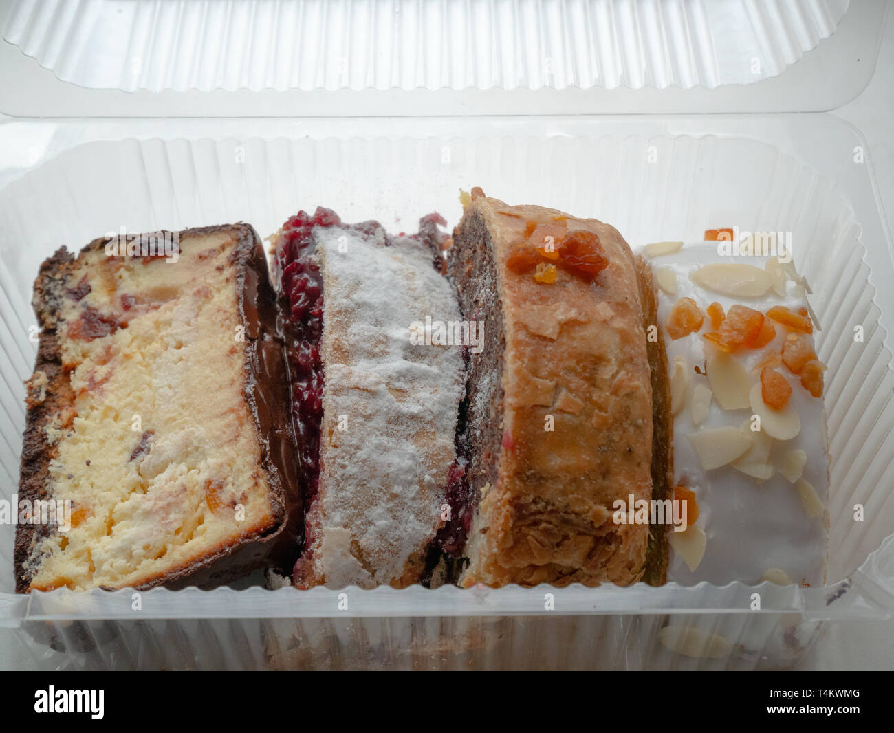 closeup of four pieces of different cakes in transparent plastic ...