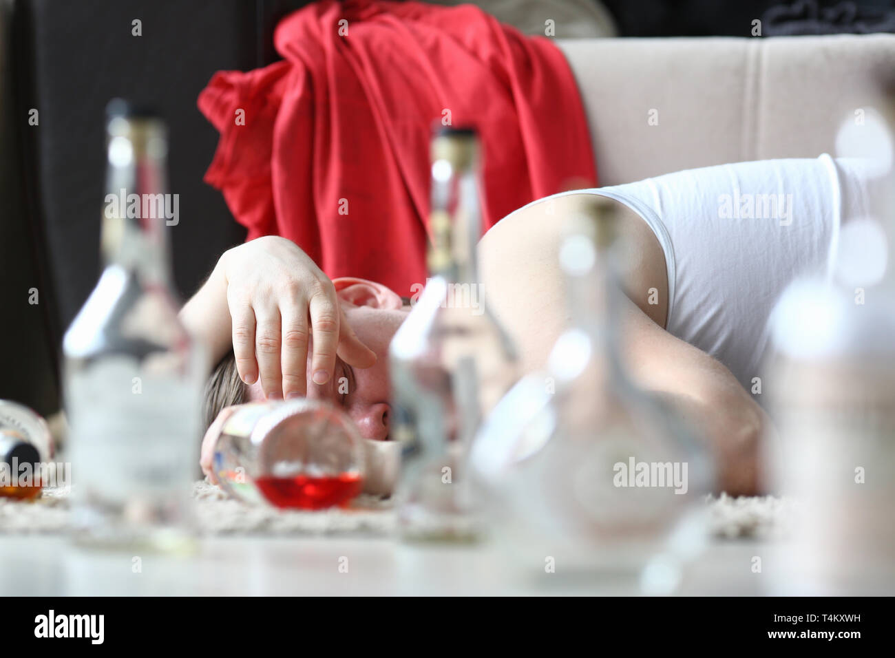 Drunken man lying among pile of empty Stock Photo