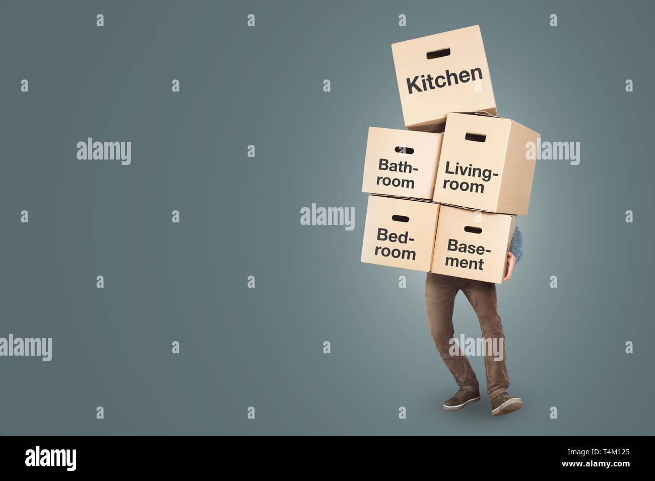 Man carrying a big stack of moving boxes labled with different rooms Stock Photo