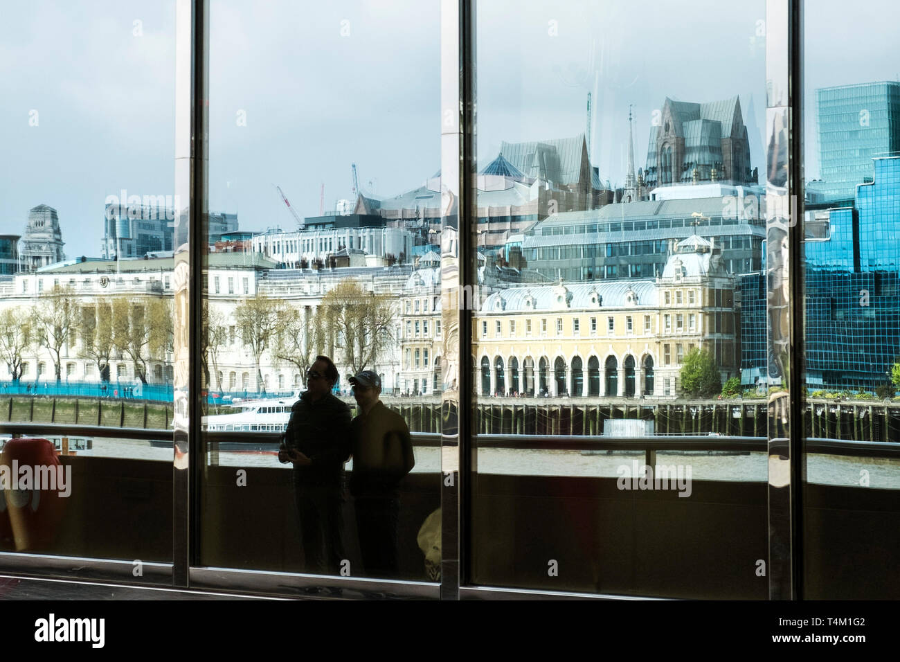 The distorted reflections of buildings on the Embankment seen in large glass windows in a building on the South Bank in London. Stock Photo