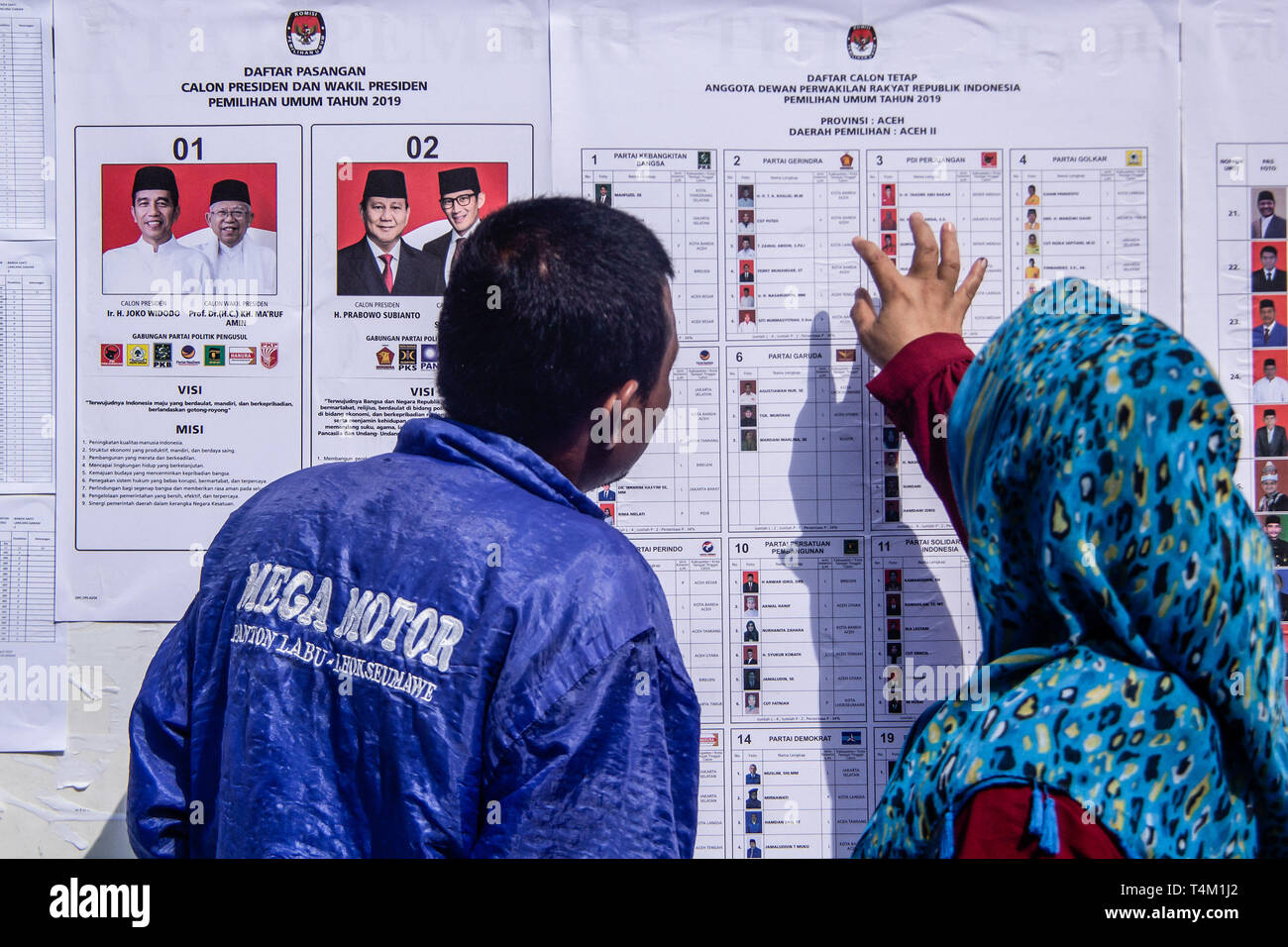 Residents seen looking at the board of president, vice president and parliament candidates. Election Day in Lhokseumawe, Aceh province, Indonesia. Millions of Indonesians will go to the polls to elect candidates and parliamentarians who will lead Indonesia in the next five years. Stock Photo