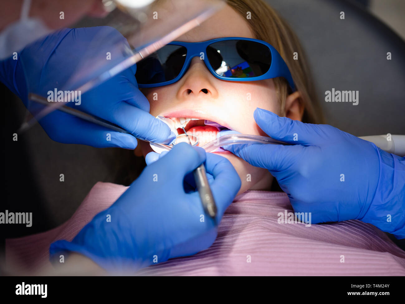 Dentist performing dental filling procedure to a little girl in