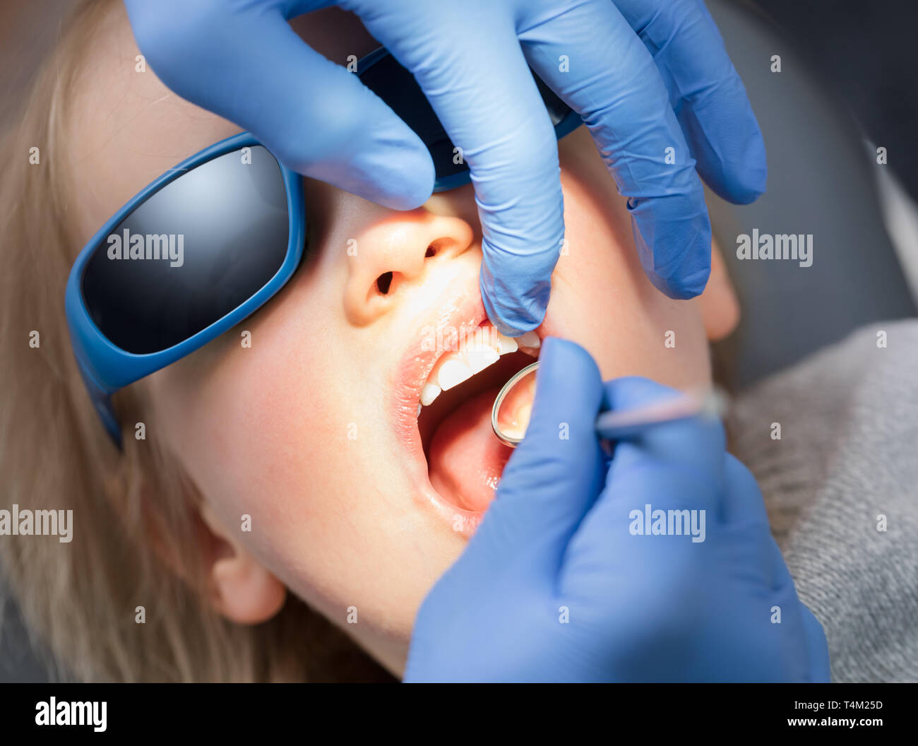 Dentist examining teeth of a little girl in pediatric dental clinic
